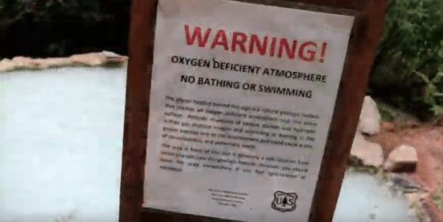 A warning sign about oxygen deficiency, prohibiting bathing or swimming in the area.