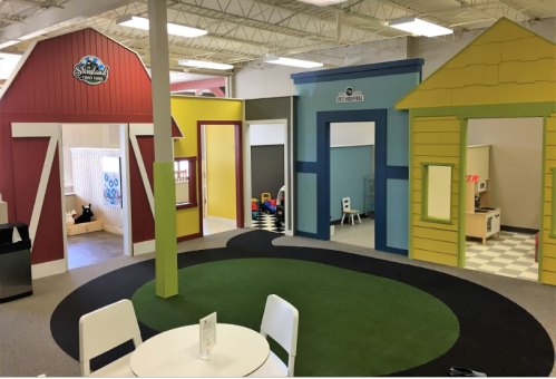 Colorful play area with three themed playhouses and a green carpet, designed for children's activities.