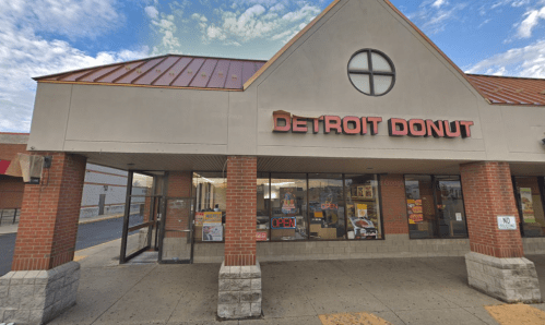 Exterior of Detroit Donut shop with a red roof, large windows, and a sign indicating it's open.