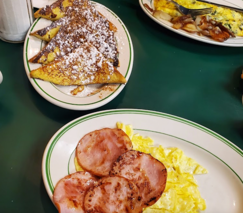 A plate of scrambled eggs and ham, with a side of French toast dusted with powdered sugar.