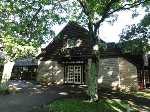 A rustic lodge with a stone and wood exterior, surrounded by trees and greenery. "Big Meadows Lodge" sign visible.