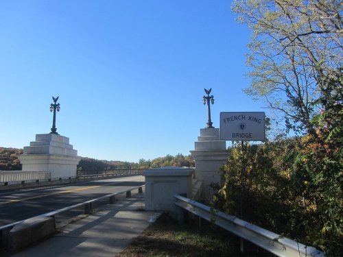 View of the French King Bridge entrance, featuring decorative pillars and a clear blue sky.