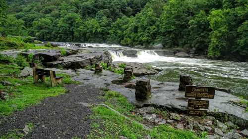 A scenic river with rapids, surrounded by lush green trees, featuring warning signs and rocky terrain.