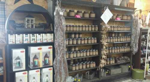 A cozy shop display featuring shelves of candles, lanterns, and decorative items in a rustic setting.