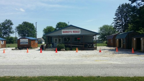 A resale shop with a sign reading "Markey's Resale," surrounded by orange cones and small wooden buildings.