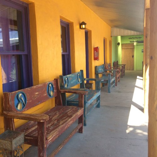 Colorful hallway with yellow walls and wooden benches, featuring purple accents and a door at the end.