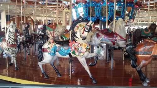 A colorful carousel featuring intricately designed horses and zebras on a polished wooden floor.