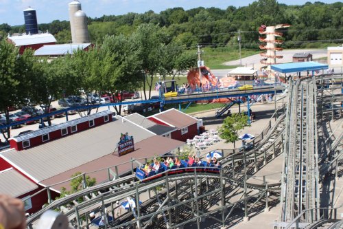Aerial view of a theme park featuring a roller coaster, water slide, and surrounding greenery.