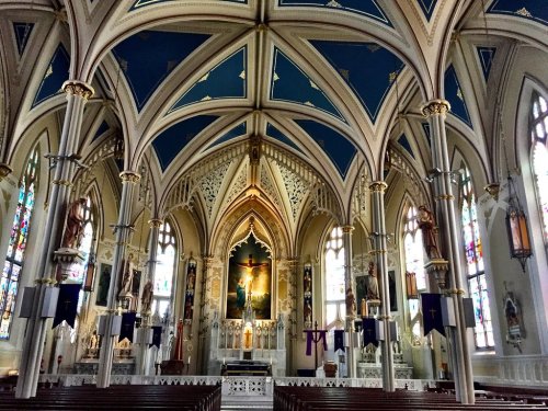 Interior of a grand church featuring ornate arches, stained glass windows, and a central altar with religious artwork.