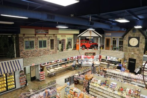 A grocery store interior with a vintage car display, meat section, and various food aisles under a blue ceiling.