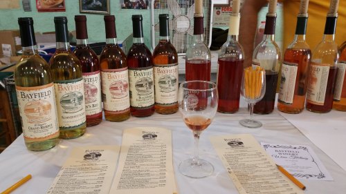 A display of various Bayfield wines with a glass and tasting menu on a table.