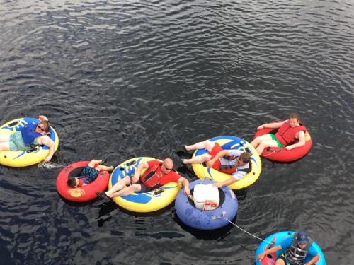 A group of people relaxes on colorful inner tubes in a body of water, enjoying a sunny day.