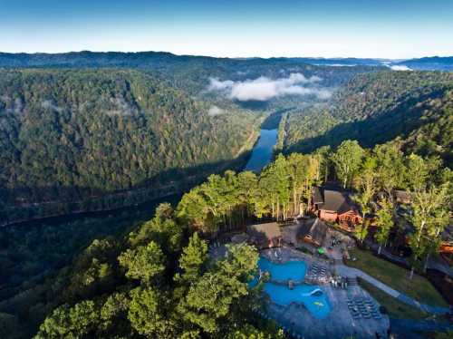 Aerial view of a scenic landscape featuring a river, lush green hills, and a pool area surrounded by trees.