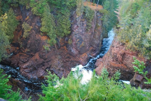 A scenic view of a rocky gorge with a flowing river surrounded by lush green trees.