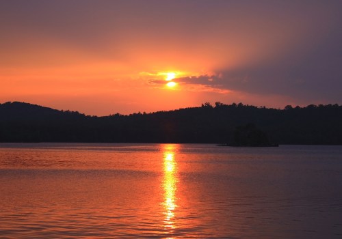 A serene sunset over a calm lake, with vibrant orange and purple hues reflecting on the water's surface.