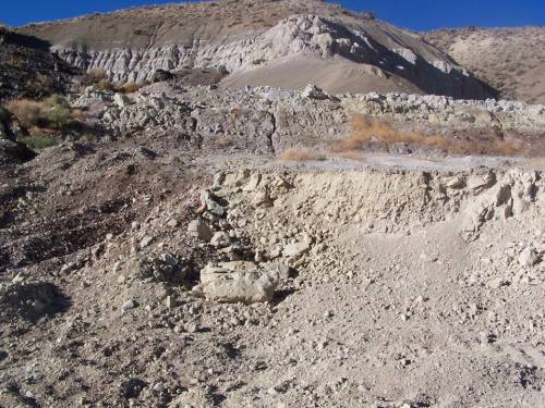 A rocky, barren landscape with steep hills and dry soil under a clear blue sky.