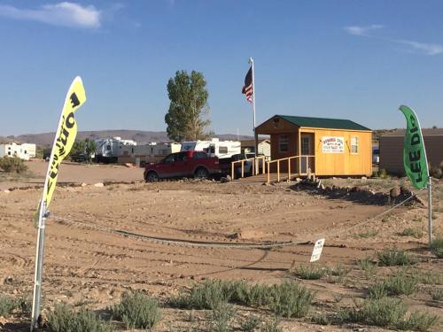 A small yellow building with a flag, surrounded by desert landscape and signs indicating services and fees.