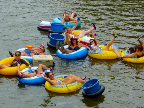 A group of people relaxing on colorful inner tubes in a river, enjoying a sunny day.