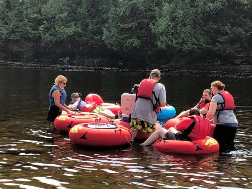 A group of people in life jackets enjoying a day on the water, sitting on colorful inner tubes.