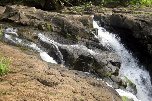 A serene waterfall cascading over rocky terrain, surrounded by lush greenery.