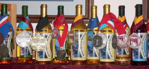 A row of wine bottles adorned with various medals and ribbons, showcasing awards and achievements.
