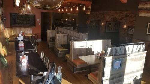 A cozy restaurant interior with wooden booths, warm lighting, and a chalkboard menu on the wall.