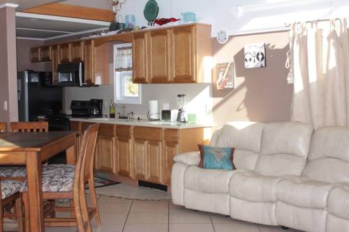 Bright kitchen with wooden cabinets, a dining table, and a light-colored couch in a cozy living space.