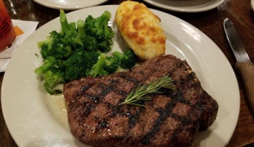 A plate featuring a grilled steak, broccoli, and a baked potato topped with cheese.