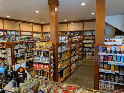 A well-organized grocery store interior with shelves stocked with various food products and beverages.