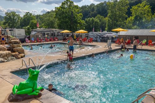 A lively pool scene with children playing, a green frog fountain, and lounge chairs under yellow umbrellas.