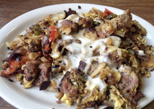 A plate of mixed breakfast hash with potatoes, sausage, peppers, and melted cheese.