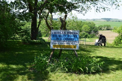 Sign for Charles Mound, the highest point in Illinois, with scenic greenery and a distant view of rolling hills.