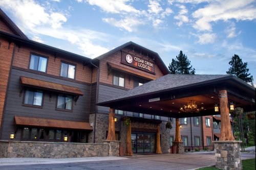 Exterior view of Cedar Creek Lodge, featuring a wooden entrance and stone accents under a blue sky.