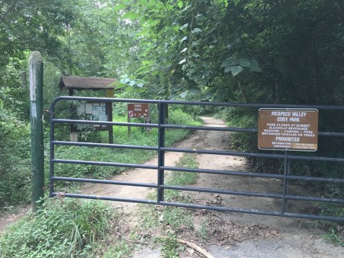 A gated entrance to Paynesville Valley State Park, with signs indicating trail access and prohibited activities.