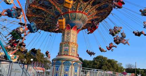 A colorful swing ride at a fair, with people enjoying the view as they soar through the air against a clear sky.