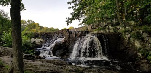 A serene waterfall cascading over rocky terrain, surrounded by lush greenery and trees.