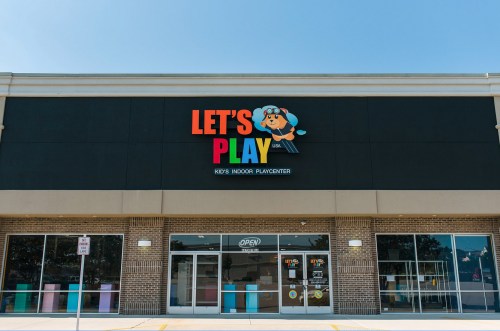 Exterior of a colorful children's indoor play center named "Let's Play," featuring large signage and open entrance.