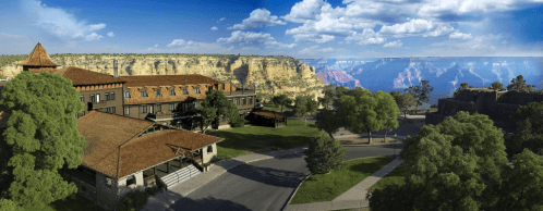 A scenic view of a lodge near the Grand Canyon, surrounded by trees and cliffs under a blue sky with clouds.