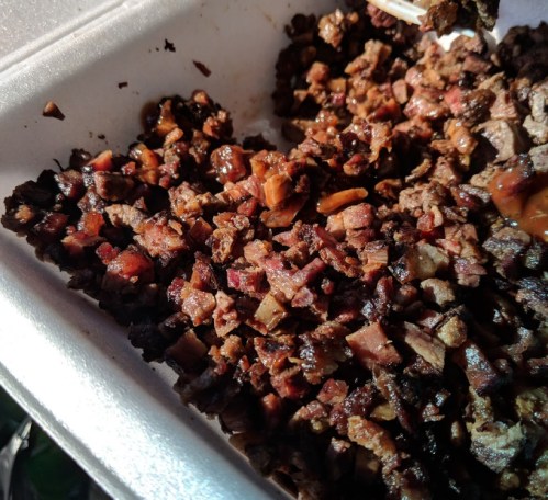 Chopped, cooked meat in a white takeout container, with a mix of dark and light pieces.
