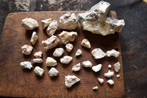 A collection of various rocks and minerals arranged on a wooden surface.