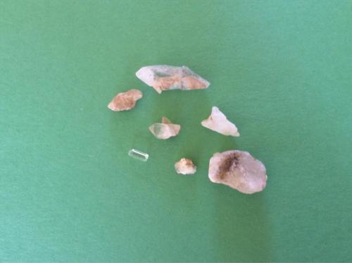 A collection of various small rocks and crystals arranged on a green background.