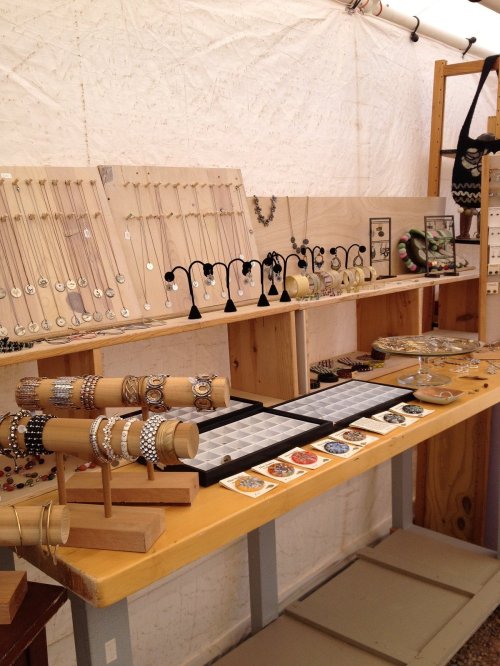 A display of various jewelry pieces, including necklaces, bracelets, and earrings, arranged on wooden stands and trays.