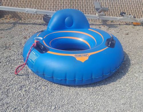 A blue inflatable tube with orange accents, resting on gravel, ready for water activities.