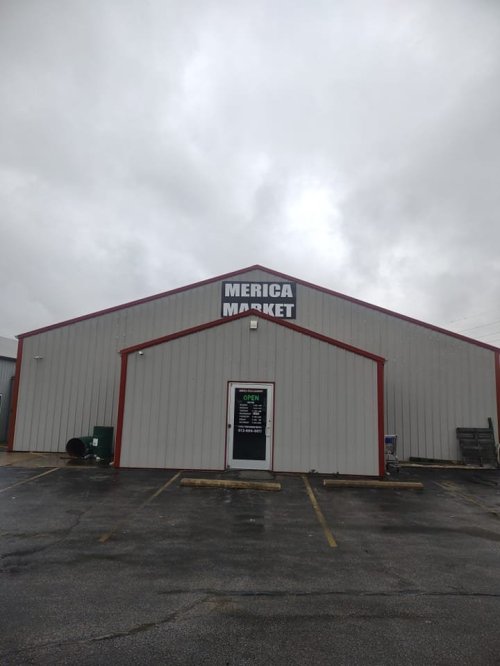 Exterior of a building labeled "Merica Market," with a cloudy sky and empty parking lot.