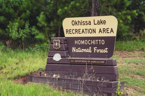Sign for Okhissa Lake Recreation Area in Homochitto National Forest, featuring U.S. Department of Agriculture emblem.