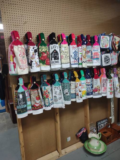 A display of colorful kitchen towels hanging on a pegboard, featuring various designs and patterns.