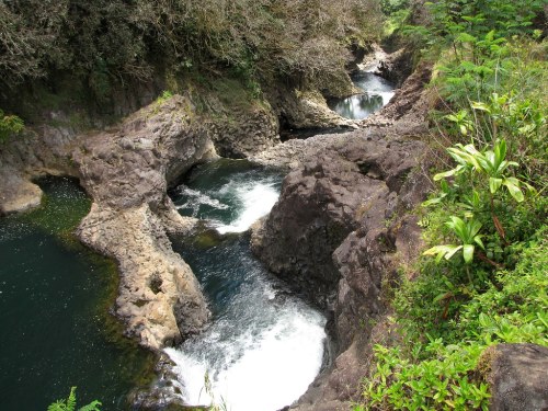 A serene landscape featuring rocky formations and flowing water in a lush, green environment.
