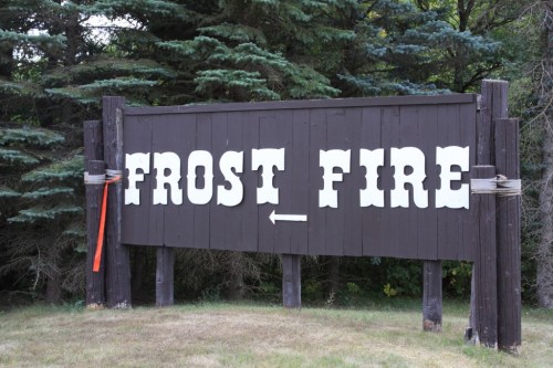 A wooden sign reading "FROST FIRE" with an arrow, surrounded by trees and grass.