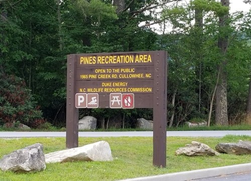 Sign for Pines Recreation Area in Cullowhee, NC, with information on public access and local organizations.