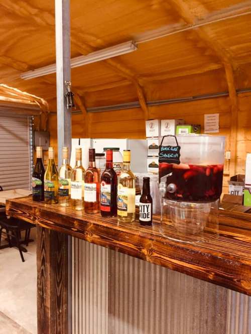 A wooden bar with various bottles of wine and a pitcher of sangria in a cozy, rustic setting.